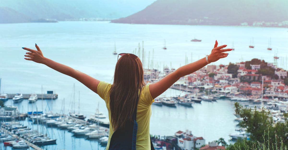 Traveling aboard an ocean liner like in The Royal Tenenbaums? - Woman Raising Her Hands Facing Cityscape Near Body of Water Traveling aboard an ocean liner like in The Royal Tenenbaums? - Woman Raising Her Hands Facing Cityscape Near Body of Water