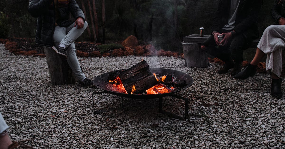 Traveling from cold region to warm region; tips regarding clothing? - Unrecognizable travelers sitting near campfire in woods Traveling from cold region to warm region; tips regarding clothing? - Unrecognizable travelers sitting near campfire in woods