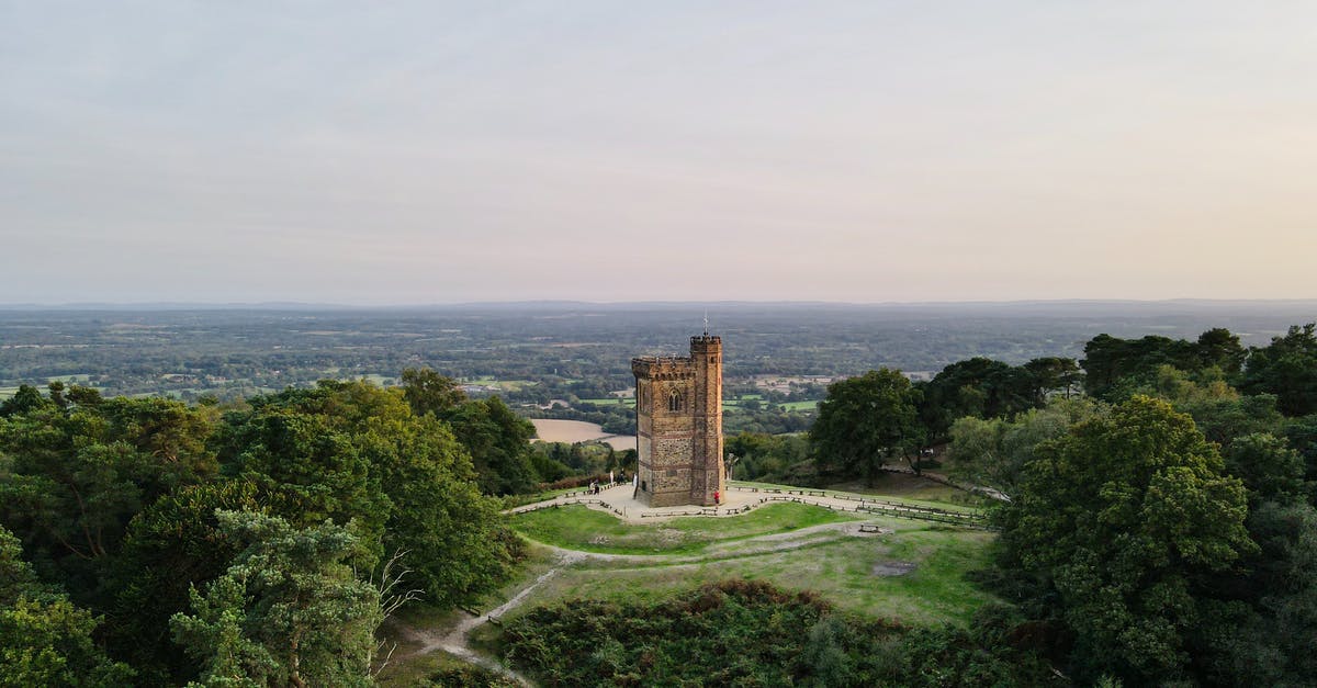Traveling from United States to England twice within one year - Gothic medieval tower on green hill under sundown sky Traveling from United States to England twice within one year - Gothic medieval tower on green hill under sundown sky