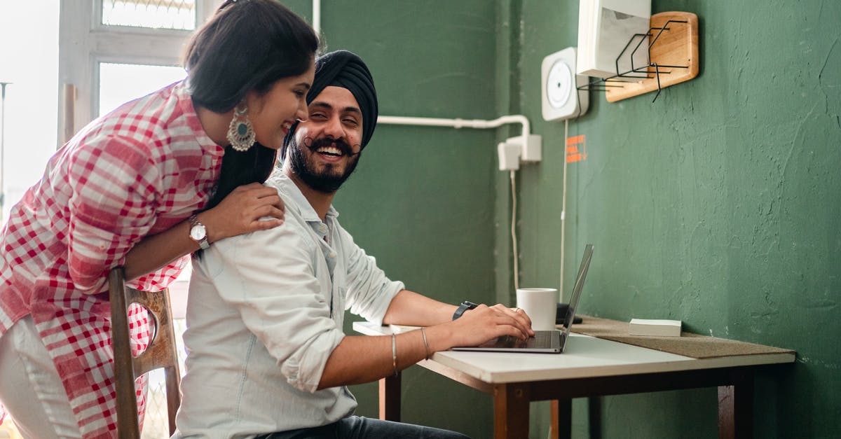 Traveling inside Schengen without a ticket to fly back home (Venezuela) - Cheerful ethnic couple using laptop at table on kitchen Traveling inside Schengen without a ticket to fly back home (Venezuela) - Cheerful ethnic couple using laptop at table on kitchen