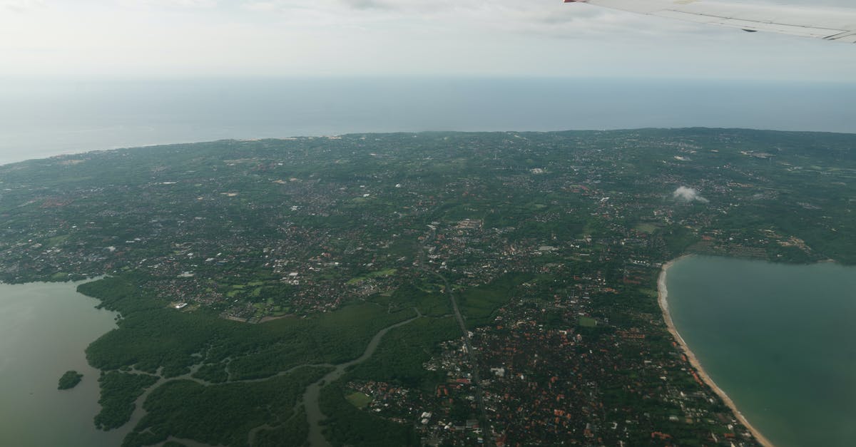Traveling to cities with extremely high air pollution - Wing of aircraft flying over coastal city Traveling to cities with extremely high air pollution - Wing of aircraft flying over coastal city