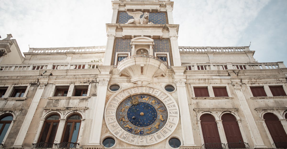 Travelling from Venice to Budapest, making a stop in Croatia - From below amazing view of famous old St. Marks Clocktower with cozy windows and stucco work against blue sky Travelling from Venice to Budapest, making a stop in Croatia - From below amazing view of famous old St. Marks Clocktower with cozy windows and stucco work against blue sky