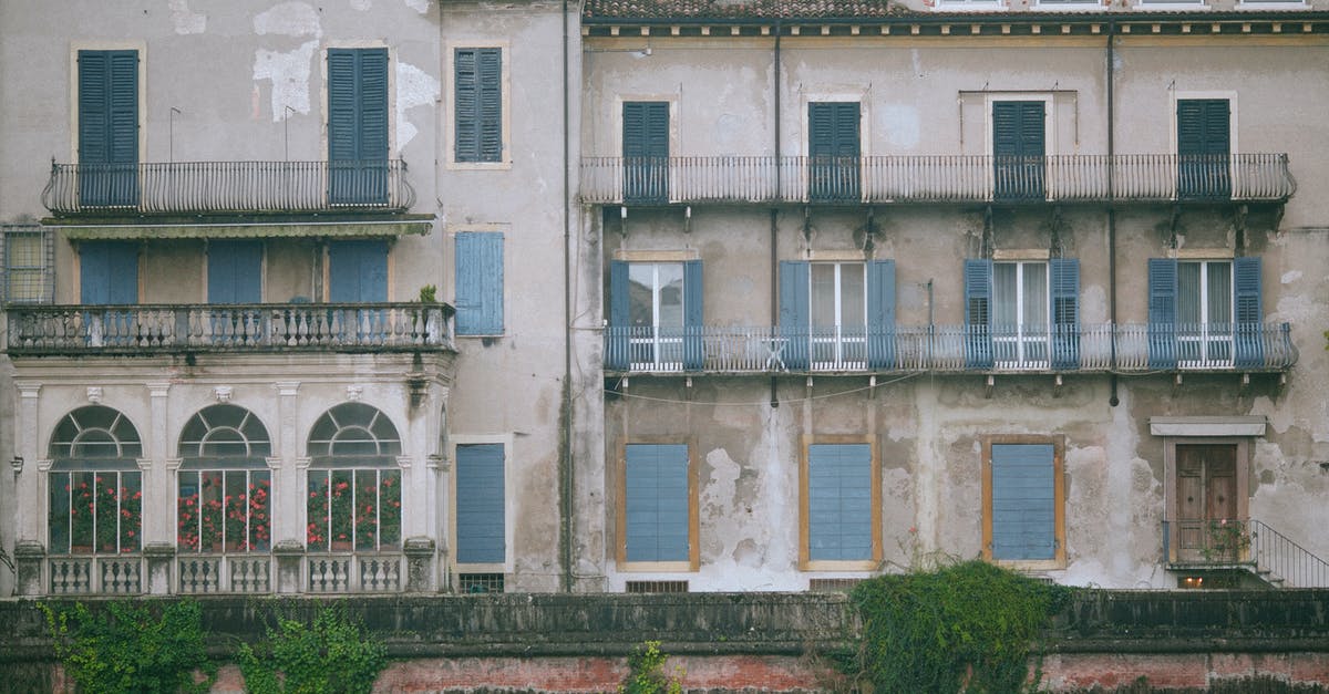 Travelling inside Schengen area after the visa expires-before the residence permit is issued? [closed] - Shabby old building decorated and windows with balconies and fence with green plants in city in daytime