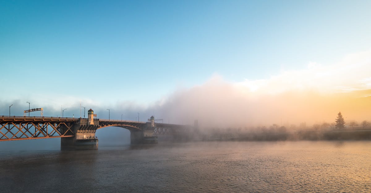 Travelling to Bend, Oregon from Portland in winter - Magnificent scenery of famous Burnside Bridge crossing rippling river and hidden under fog against colorful sunset sky Travelling to Bend, Oregon from Portland in winter - Magnificent scenery of famous Burnside Bridge crossing rippling river and hidden under fog against colorful sunset sky