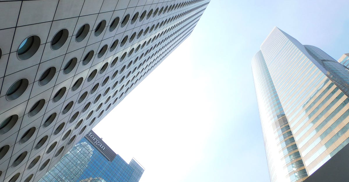 Travelling to China / Hong Kong with criminal conviction from Australia - From below of tall tower with round windows located in Hong Kong city near various skyscrapers with glass mirrored facades against cloudless blue sky