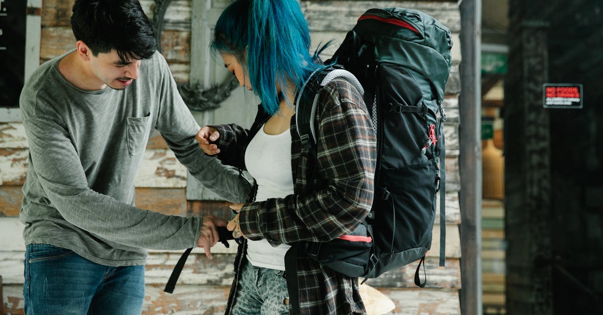 Travelling to Israel - help to divide time between areas [closed] - Side view of young multiracial couple of tourists in casual clothes carrying backpack while standing near wooden wall and preparing for travel