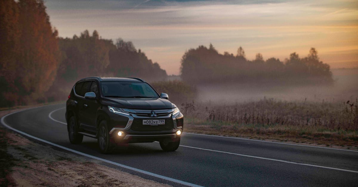 Travelling to rural areas in the US without a car - Contemporary black offroader car driving along asphalt road in peaceful foggy countryside area in dusk Travelling to rural areas in the US without a car - Contemporary black offroader car driving along asphalt road in peaceful foggy countryside area in dusk