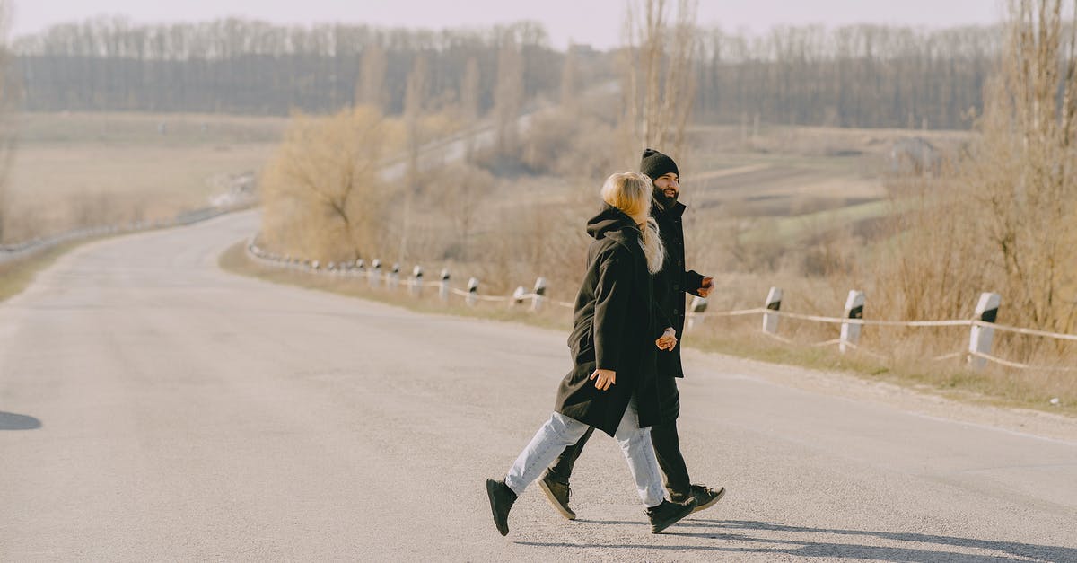 Travelling to rural areas in the US without a car - Young couple crossing road in wrong place at countryside Travelling to rural areas in the US without a car - Young couple crossing road in wrong place at countryside