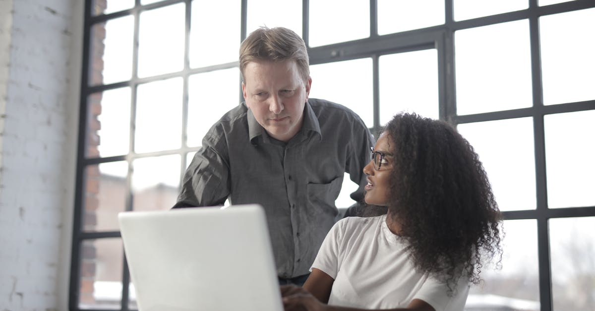 Travelling to US using B1/B2 visa annotation "B1 IN LIEU OF H" to different company - Professional adult male entrepreneur browsing netbook with young female African American colleague and discussing startup project during office work in workplace near big window