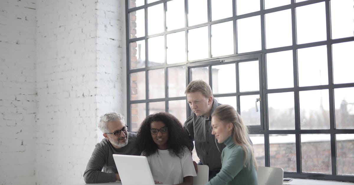 Travelling to US using B1/B2 visa annotation "B1 IN LIEU OF H" to different company - Cheerful diverse colleagues of different ages using laptop in creative workplace