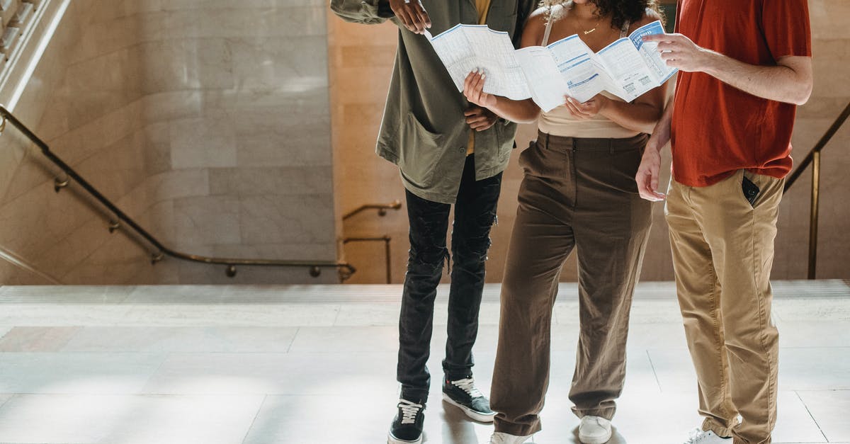 Travelling to Vietnam: how to find a local friend or travel companion? [duplicate] - Concentrated young Hispanic lady reading map while standing near staircase of old building during vacation with crop multiethnic male friends