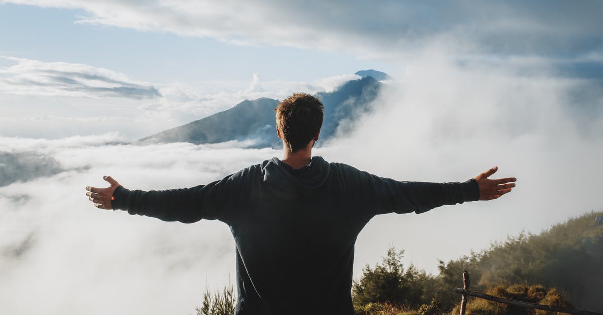 Trekking in Georgian Tusheti region? Safety? - Back view of anonymous male traveler in casual clothes standing on edge of cliff and admiring breathtaking scenery of clouds and mountain top Trekking in Georgian Tusheti region? Safety? - Back view of anonymous male traveler in casual clothes standing on edge of cliff and admiring breathtaking scenery of clouds and mountain top