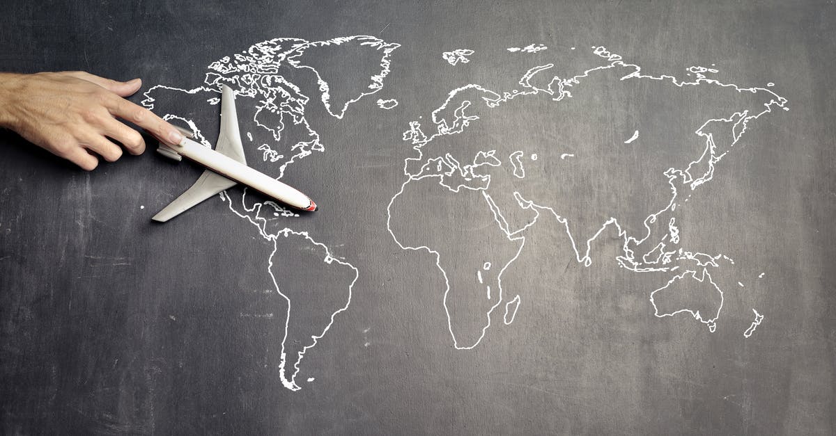 Trouble with delays with American Airlines, international travel - From above of crop anonymous person driving toy airplane on empty world map drawn on blackboard representing travel concept