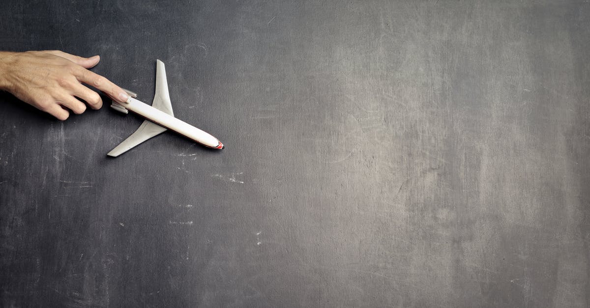 Trouble with delays with American Airlines, international travel - Top view of crop anonymous person driving toy airplane on empty blackboard while representing journey concept