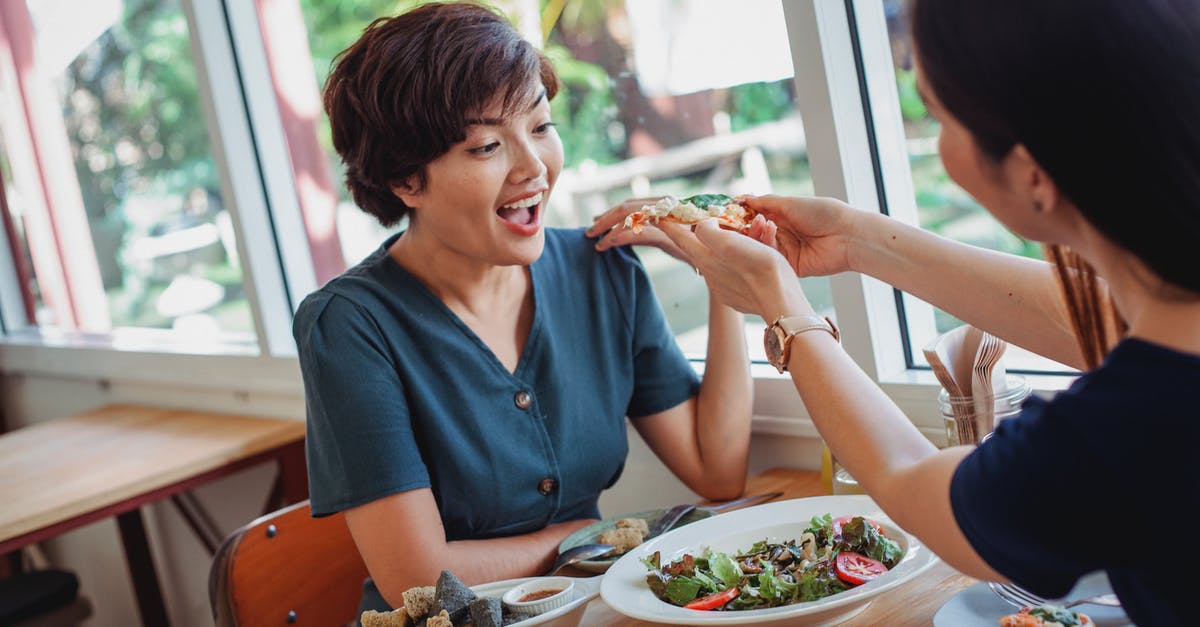 Trying to find a specific restaurant in Jerusalem - Crop woman feeding pizza to friend Trying to find a specific restaurant in Jerusalem - Crop woman feeding pizza to friend