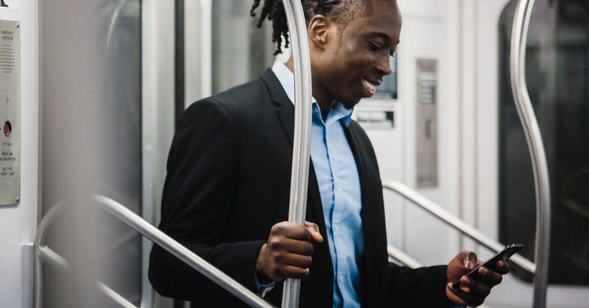 TSA canines and expedited passenger screening - Cheerful black man surfing net on mobile on subway train TSA canines and expedited passenger screening - Cheerful black man surfing net on mobile on subway train