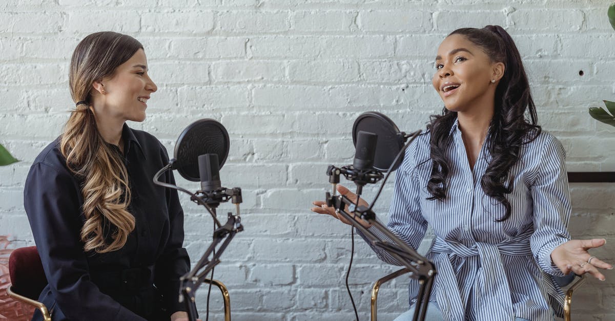 Type of visa for job interview in China - Smiling African American female guest gesticulating while having interview with journalist sitting near mic Type of visa for job interview in China - Smiling African American female guest gesticulating while having interview with journalist sitting near mic
