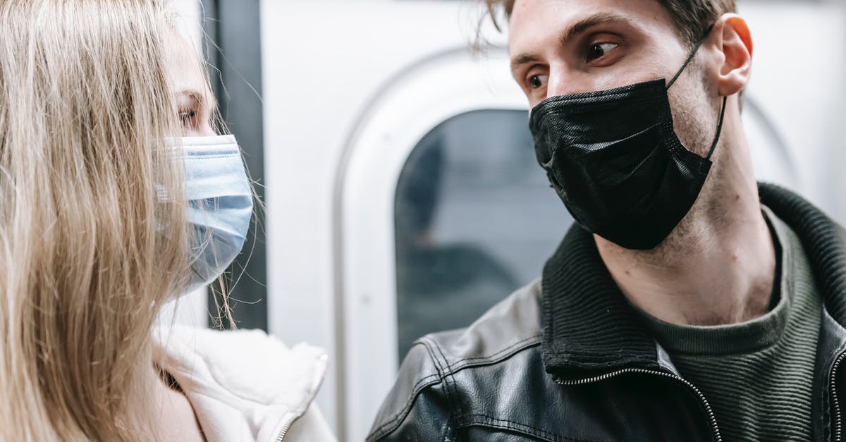 UK COVID Test-to-release programs starting date - Couple in medical masks standing in subway UK COVID Test-to-release programs starting date - Couple in medical masks standing in subway
