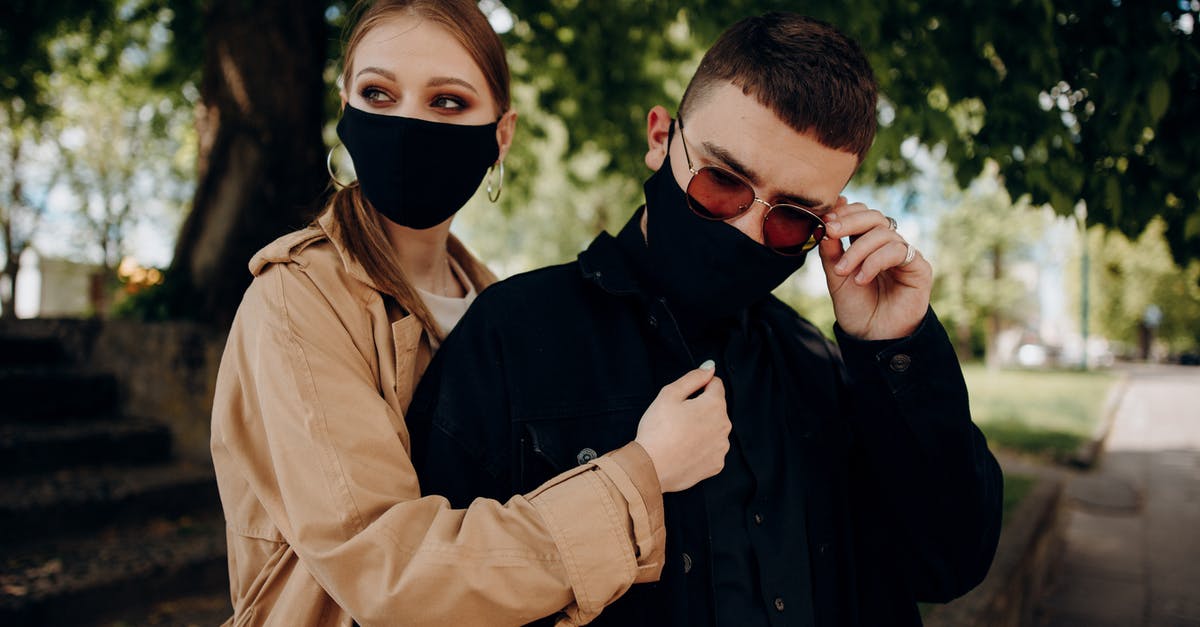 UK COVID Test-to-release programs starting date - Couple in masks embracing and looking away UK COVID Test-to-release programs starting date - Couple in masks embracing and looking away