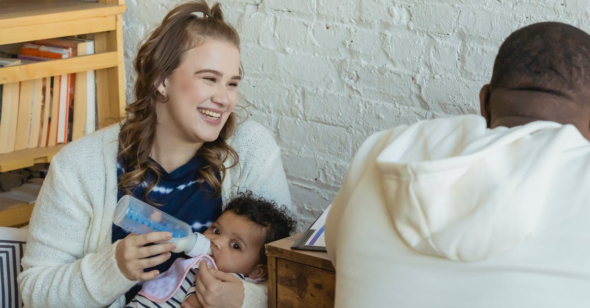 UK Family Visa rejected due to submission of falsified document [closed] - Cheerful mother feeding black baby sitting near busy father