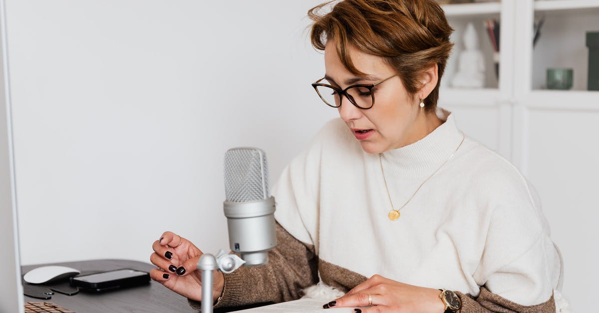 UK Short-term study visa - Female narrator in glasses reading out loud from book while sitting at desk with microphone and recording audiobook in cozy study UK Short-term study visa - Female narrator in glasses reading out loud from book while sitting at desk with microphone and recording audiobook in cozy study