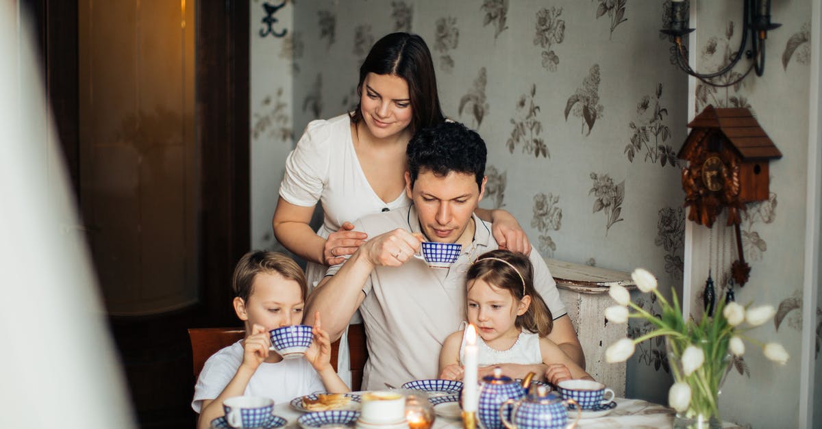 UK Standard Visitor visa for wife and 3-year-old daughter [closed] - Contented family drinking tea with crepes together while sitting at table with candles at cozy kitchen with cuckoo clock on wall
