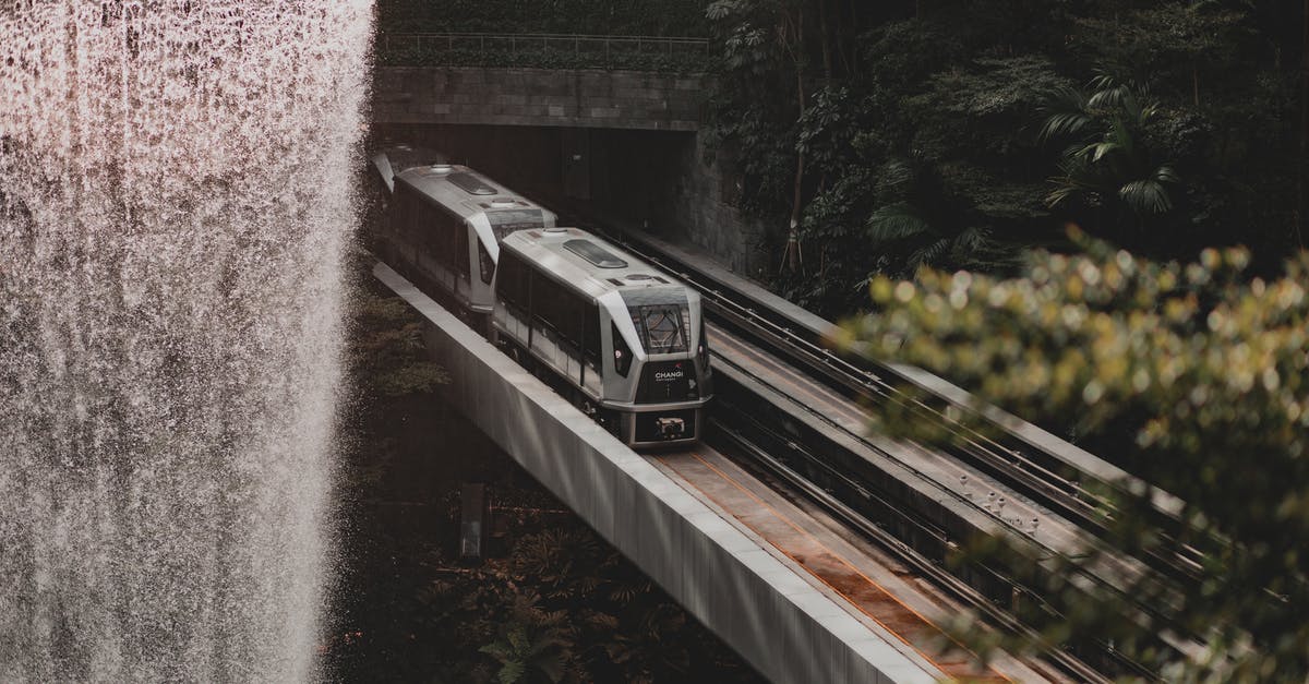 UK transit visa under processing; change of travel dates? - Scenic view of modern fast train going along railroad under waterfall bridge near lush forest trees on sunny day UK transit visa under processing; change of travel dates? - Scenic view of modern fast train going along railroad under waterfall bridge near lush forest trees on sunny day