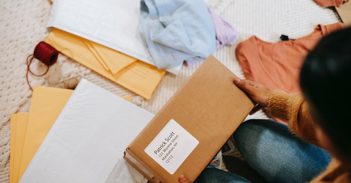 UK Visa Courier Address - Top view of crop anonymous female with carton box of parcel checking address among envelopes UK Visa Courier Address - Top view of crop anonymous female with carton box of parcel checking address among envelopes