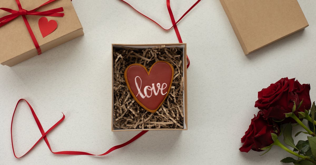UK Visa form filling - Top view of heart shaped cookie with Love word in box with decorative paper filling [laced on gray background near gift boxes with red ribbons and bouquet of roses UK Visa form filling - Top view of heart shaped cookie with Love word in box with decorative paper filling [laced on gray background near gift boxes with red ribbons and bouquet of roses