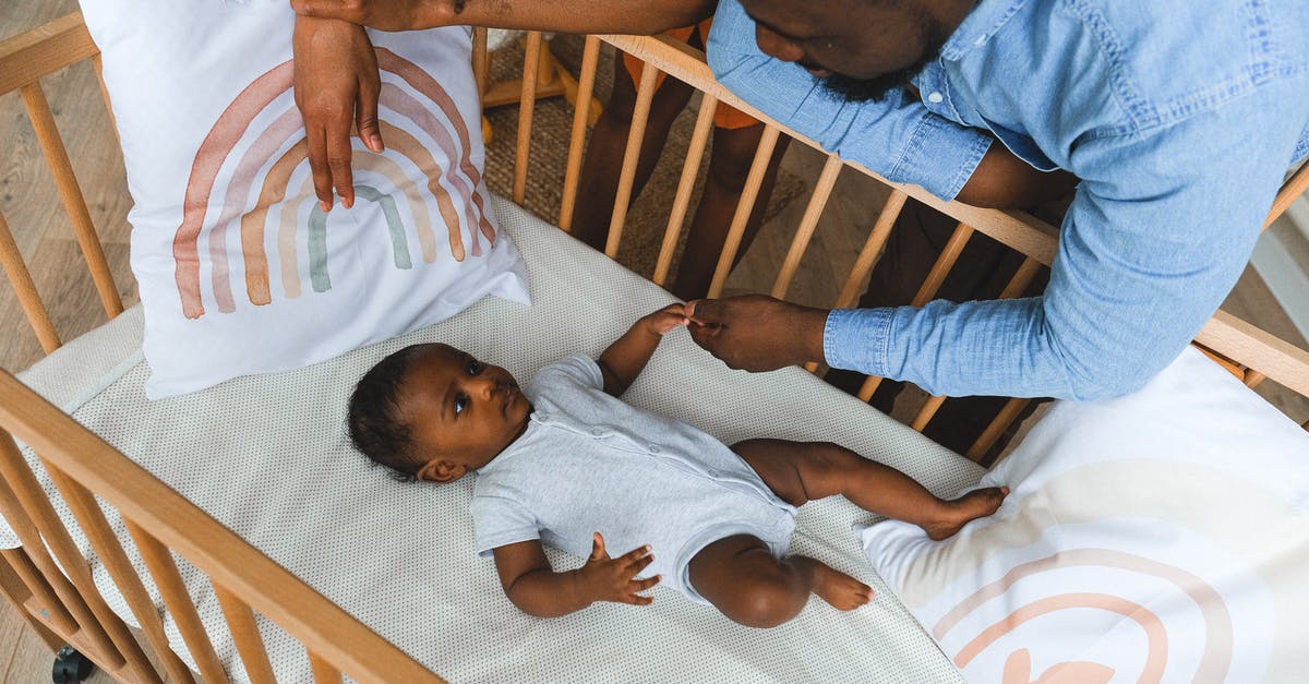 UK visit visa for an infant - how to apply if parents already hold a UK visa? - A Parent Holding Hands with a Baby in a Crib
