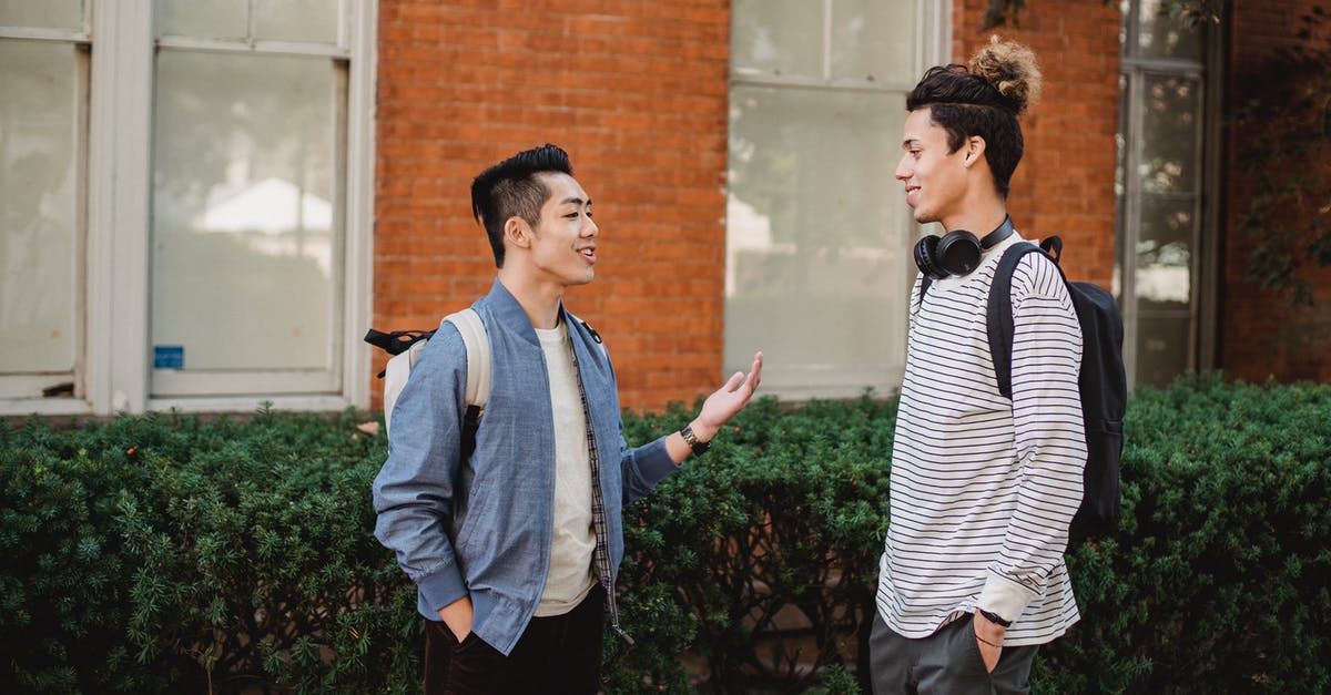 Uk visit Visa to meet sister,previously overstayed as a student in france - Cheerful multiethnic male friends chatting outside modern building
