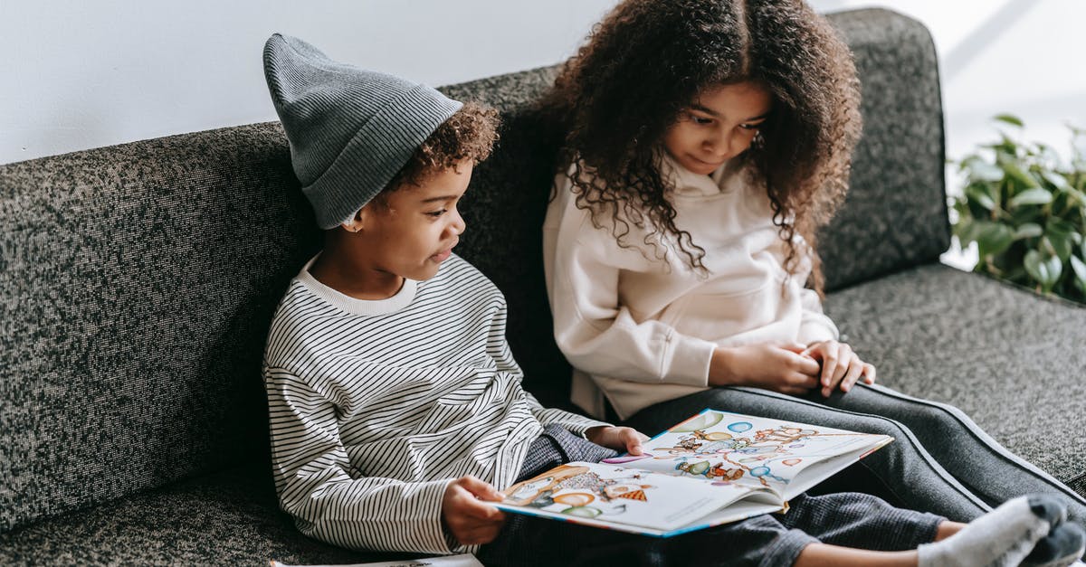 UK visitor visa, do I provide information about the children we leave at home? - Clever African American brother and sister in trendy outfits reading interesting story with pictures in book on sofa UK visitor visa, do I provide information about the children we leave at home? - Clever African American brother and sister in trendy outfits reading interesting story with pictures in book on sofa