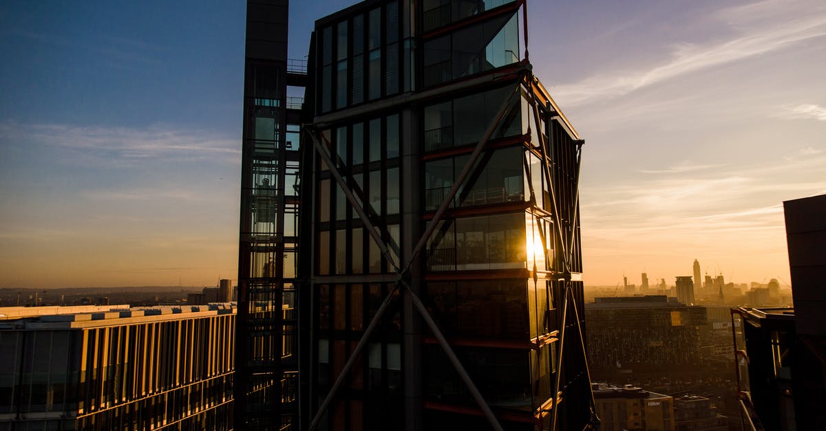 UK visitor visa without any property - Exterior of contemporary glass skyscraper against sundown sky in city UK visitor visa without any property - Exterior of contemporary glass skyscraper against sundown sky in city