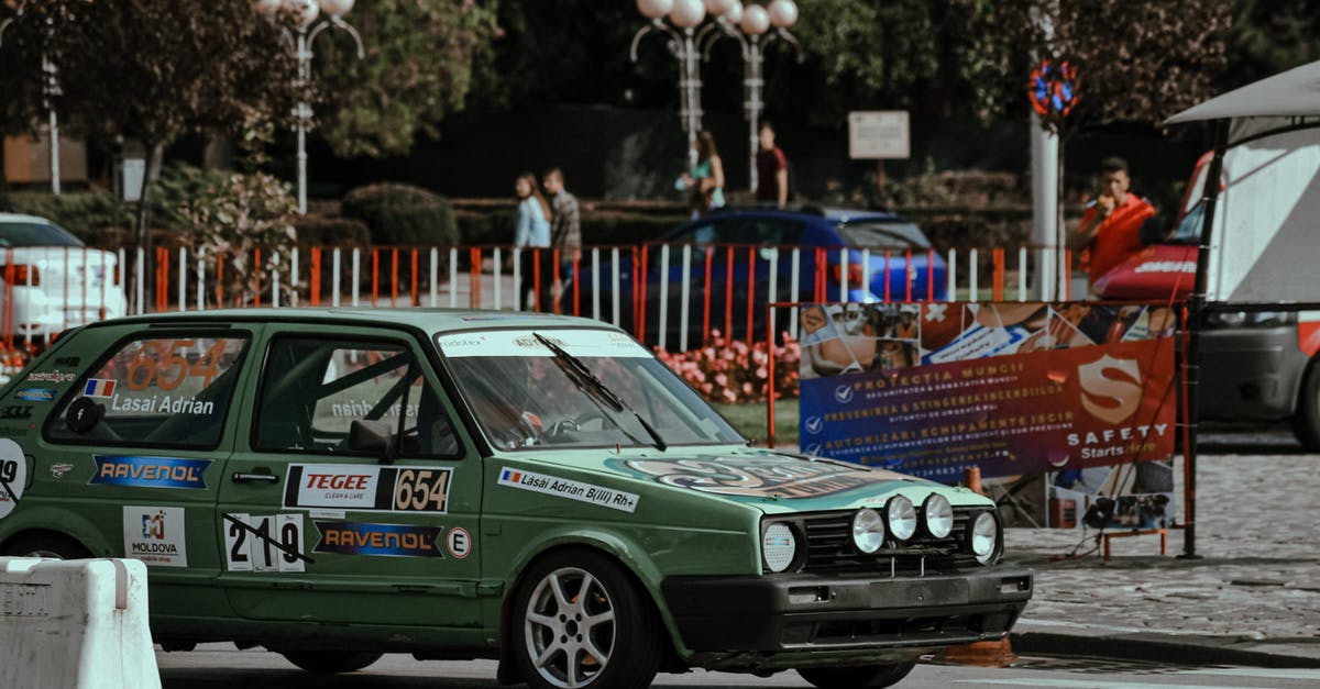 Umweltzone sticker for a car that matches restrictions but not age limit - Green racing car in stickers driving down paved roadway in sunny city center