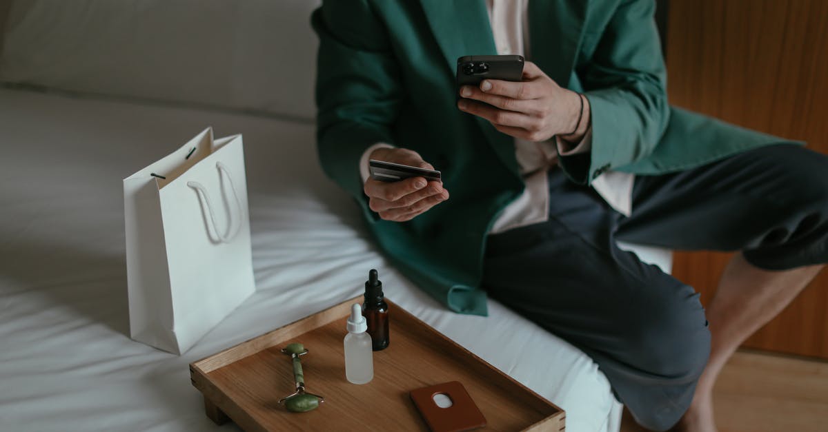 Unable to purchase online rail tickets from Busan to Seoul - Anonymous man using smartphone while placing order with credit card sitting near cosmetic products Unable to purchase online rail tickets from Busan to Seoul - Anonymous man using smartphone while placing order with credit card sitting near cosmetic products