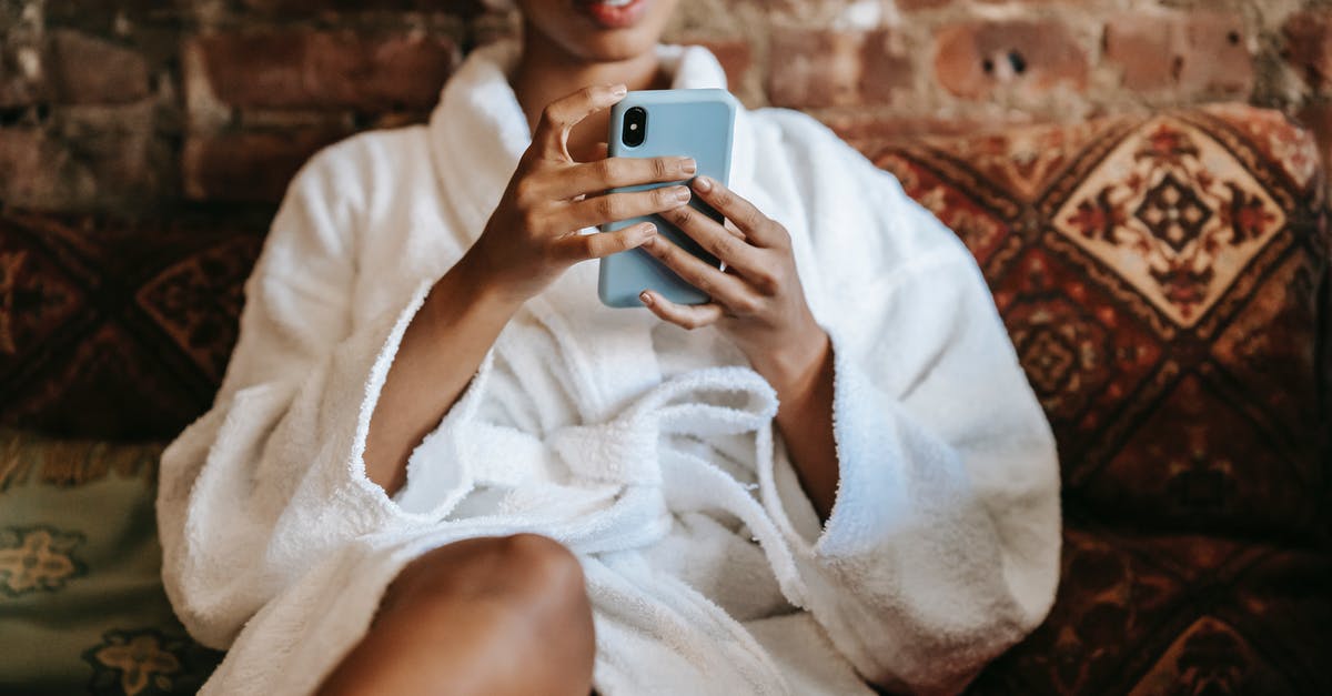 United Airlines' online check-in procedure : "stay" or "transit" for one night? - Crop ethnic woman text messaging on smartphone at home United Airlines' online check-in procedure : "stay" or "transit" for one night? - Crop ethnic woman text messaging on smartphone at home