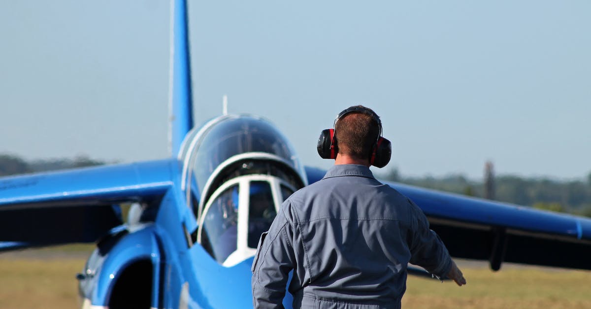 United Airlines domestic travel noise cancelling headphones carry on - Man in Noise Cancelling Headphones Approaching Blue Airpla United Airlines domestic travel noise cancelling headphones carry on - Man in Noise Cancelling Headphones Approaching Blue Airpla