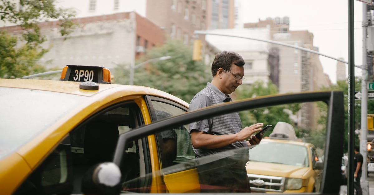 unlock a AT&T phone outside US - Calm man in glasses standing near taxi and looking at smartphone on street in city in daytime unlock a AT&T phone outside US - Calm man in glasses standing near taxi and looking at smartphone on street in city in daytime