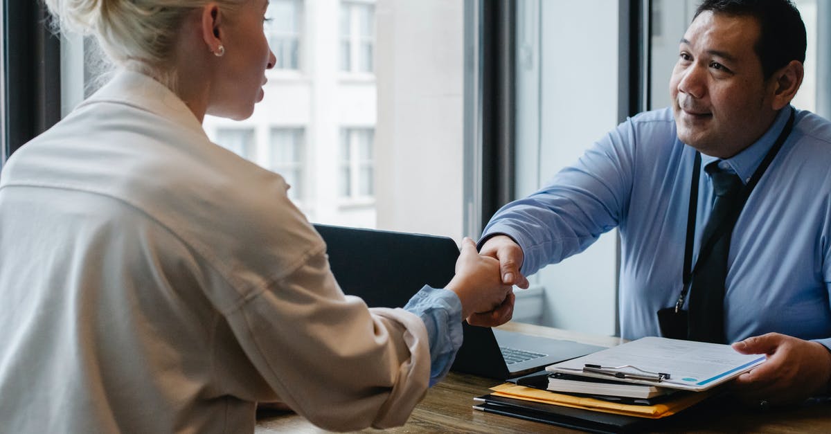 US Consulate visa interview appointment scheduling - Ethnic businessman shaking hand of applicant in office US Consulate visa interview appointment scheduling - Ethnic businessman shaking hand of applicant in office