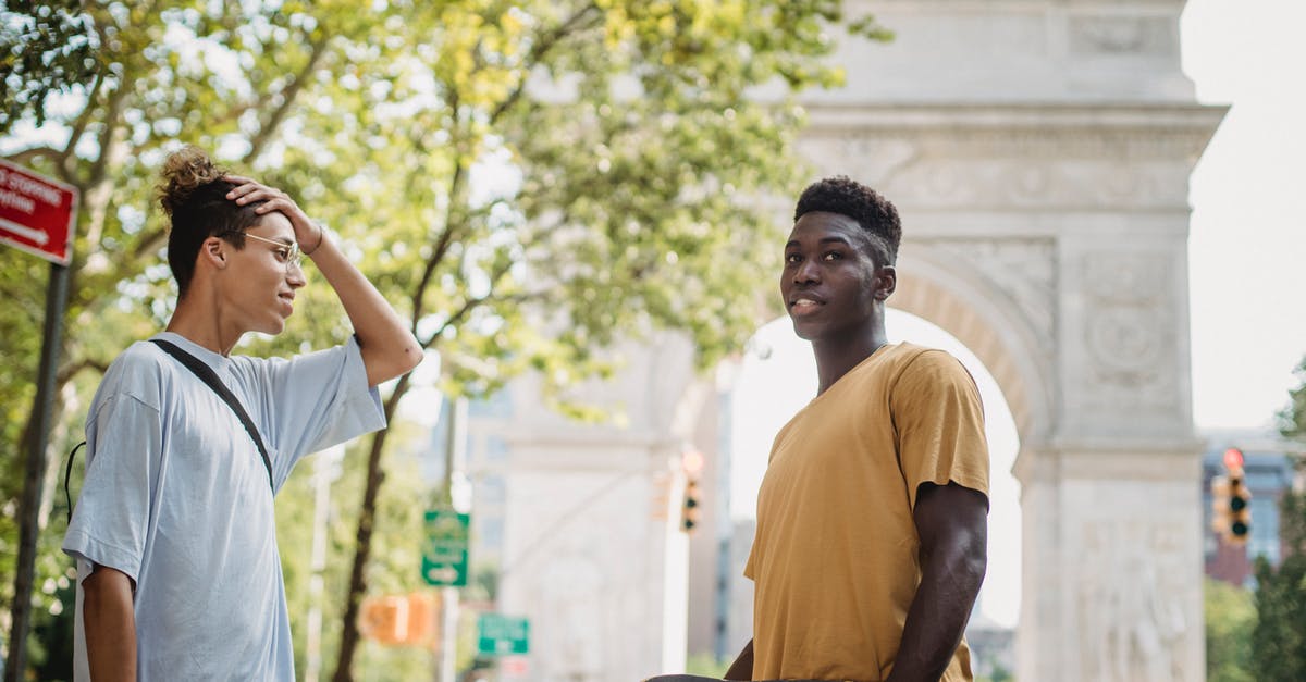 US Preclearance time at Abu Dhabi - (AUH - MAN - ORD) - Side view of young diverse male millennials in casual clothes standing on New York street near Washington Square Arch with skateboards in hands and chatting US Preclearance time at Abu Dhabi - (AUH - MAN - ORD) - Side view of young diverse male millennials in casual clothes standing on New York street near Washington Square Arch with skateboards in hands and chatting