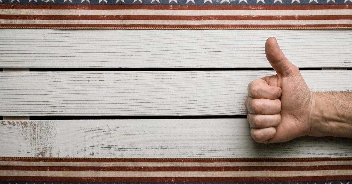 US visa approved, but passport is stuck at the US consulate? - Overhead view of crop unrecognizable male with approve gesture on wooden table between American decoration with stripes and stars US visa approved, but passport is stuck at the US consulate? - Overhead view of crop unrecognizable male with approve gesture on wooden table between American decoration with stripes and stars