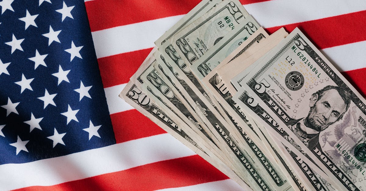 US visa from Bangkok, Thailand and wish to visit another country - Top view of various dollar banknotes placed on flag of United States of America US visa from Bangkok, Thailand and wish to visit another country - Top view of various dollar banknotes placed on flag of United States of America