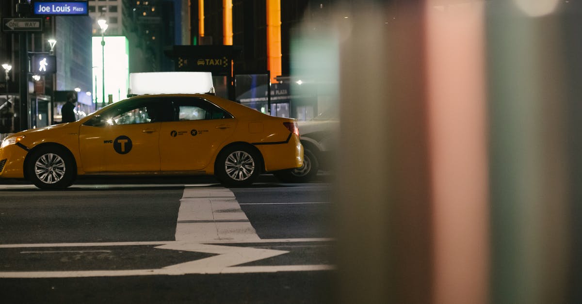 USA car rental one-way fee - Contemporary taxi car driving on city street at night USA car rental one-way fee - Contemporary taxi car driving on city street at night