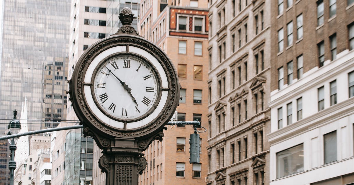 USA E-3 and B1/B2 visa processing time on entry - Vintage street clock on pillar located near residential buildings and skyscrapers in downtown of New York city in financial district USA E-3 and B1/B2 visa processing time on entry - Vintage street clock on pillar located near residential buildings and skyscrapers in downtown of New York city in financial district