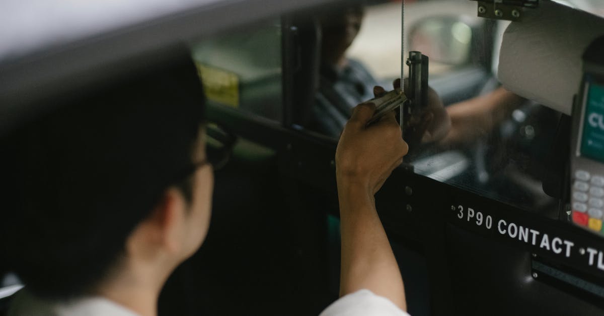 USA fingerprint on arrival - High angle of crop young male passenger in white shirt sitting in automobile and giving dollars to driver USA fingerprint on arrival - High angle of crop young male passenger in white shirt sitting in automobile and giving dollars to driver