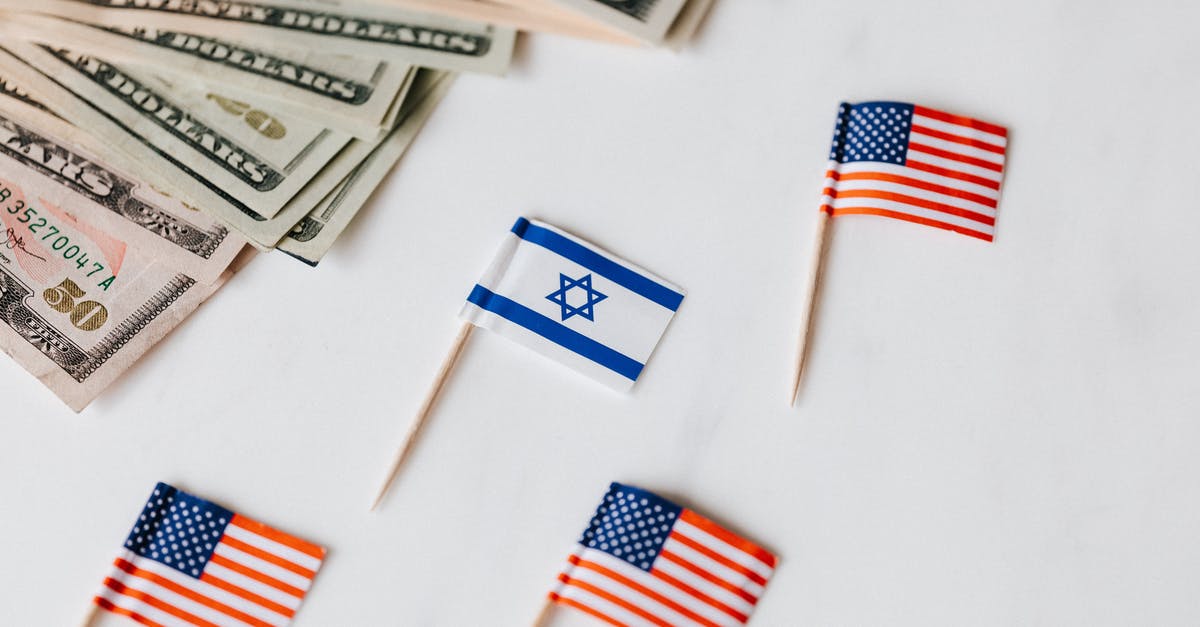 USA J1-visa: apply in country different form passport nationality - From above closeup of Israeli and American flags on toothpicks and different nominal pars of dollar banknotes on white background USA J1-visa: apply in country different form passport nationality - From above closeup of Israeli and American flags on toothpicks and different nominal pars of dollar banknotes on white background