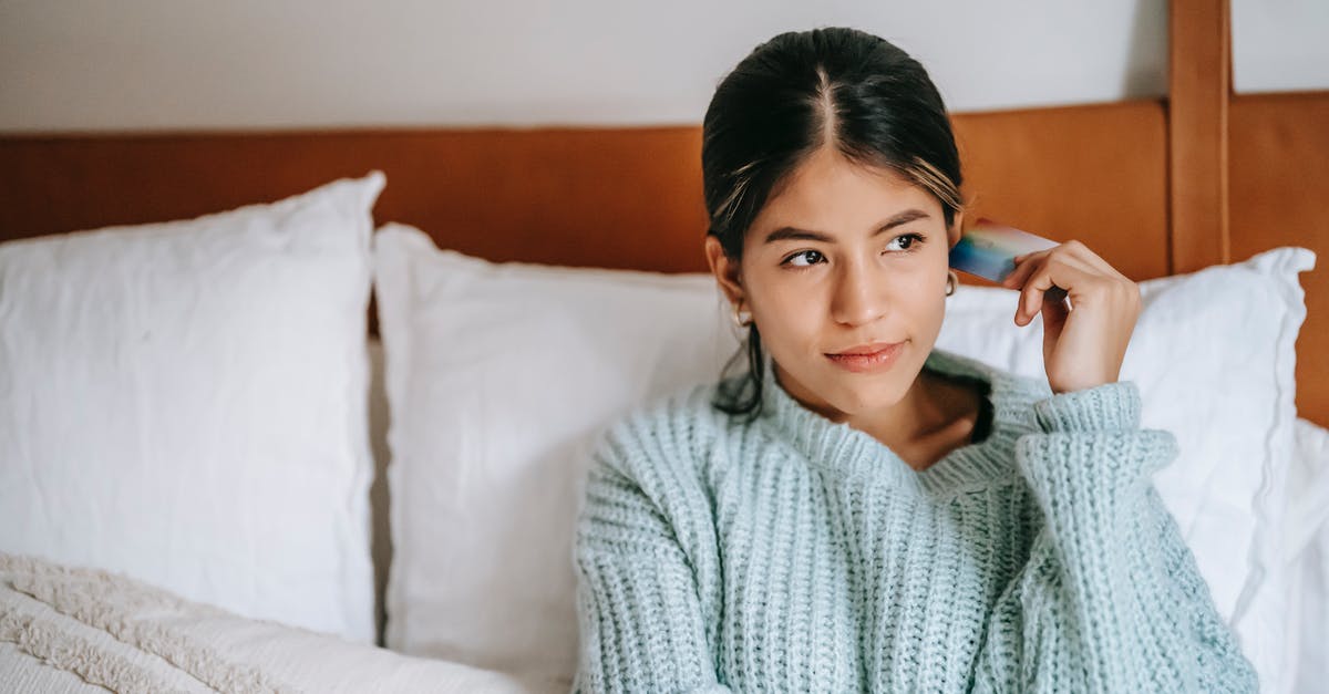 Used a debit card to book on booking.com for a hotel for six months that I thought had free cancellations [closed] - Young contemplative ethnic female with plastic card sitting on soft bed while looking away in house