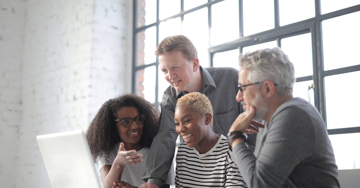 Using a Schengen type D visa for a short internship in a different country - Positive diverse coworkers of different ages sitting at table and browsing laptop while discussing project in modern workspace with big window
