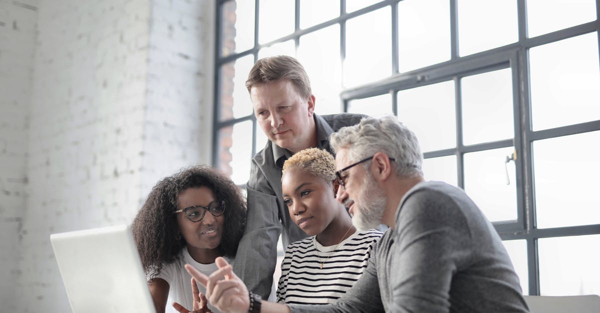 Using a Schengen type D visa for a short internship in a different country - Multiracial colleagues of different ages sitting at table in modern workplace while watching project on laptop and discussing with active gesticulation