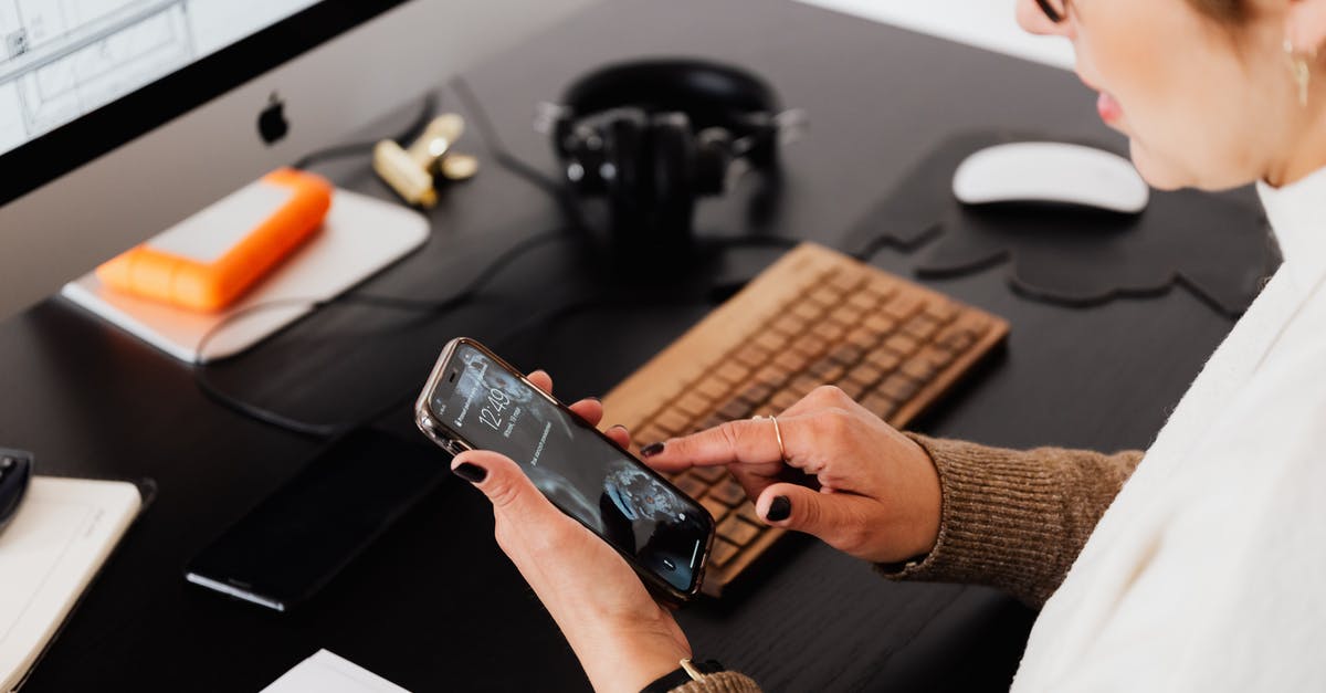 Using different passports for Entry/Exit when passport-officials from both countries sit at the same desk - Crop woman using smartphone while working at computer Using different passports for Entry/Exit when passport-officials from both countries sit at the same desk - Crop woman using smartphone while working at computer